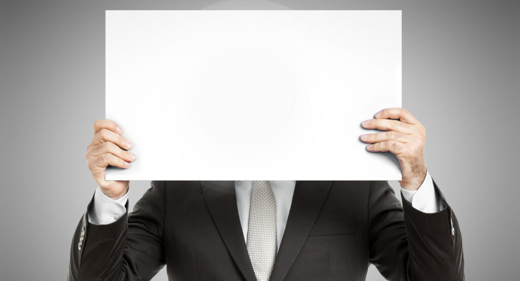 A business man holding a paper in front of his face with a smiley sign on it