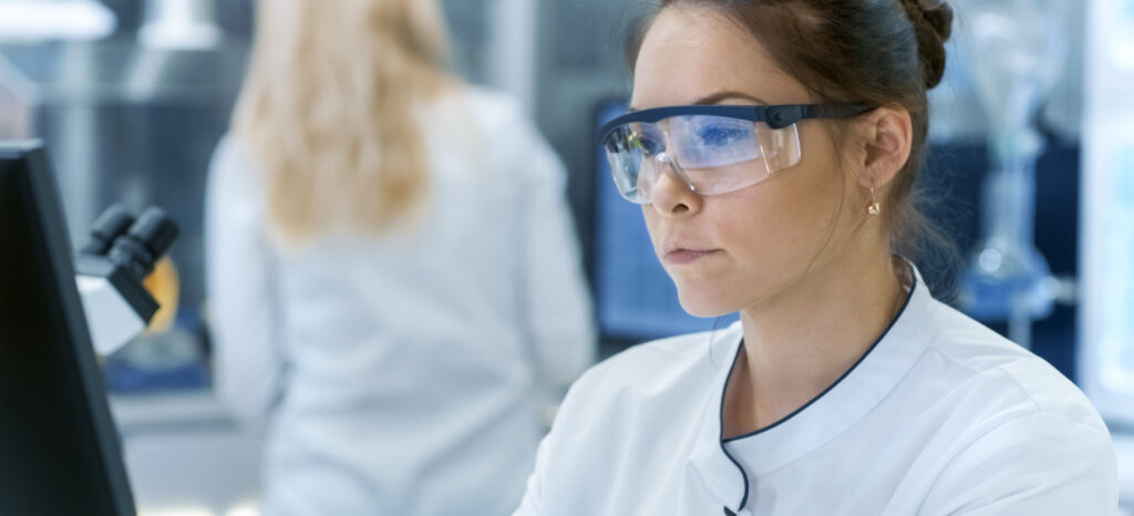 Safety rules. Smart young woman wearing special protective glasses while working in the lab