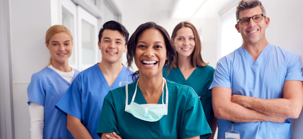 Portrait Of Laughing Multi-Cultural Medical Team Standing In Hospital Corridor