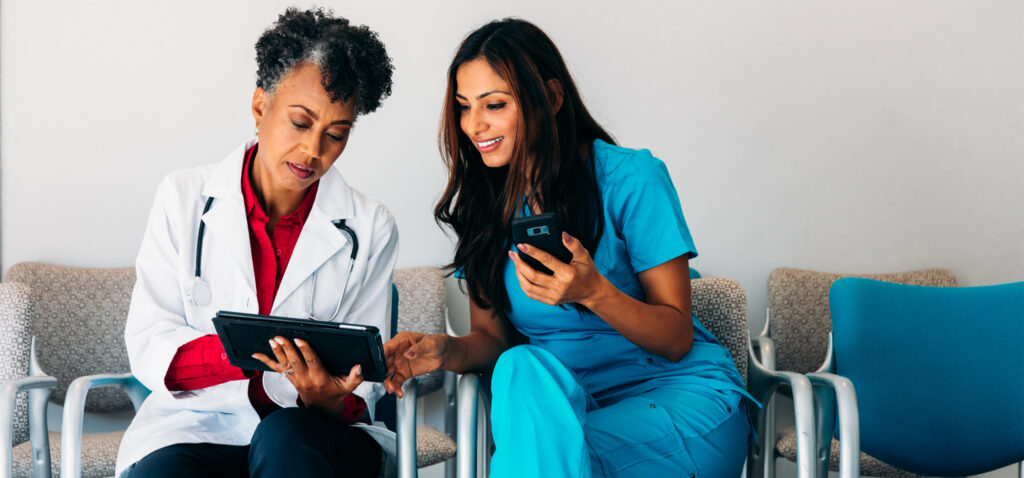 Shot of a young doctor using a digital tablet in a hospital with her colleagues in the background.